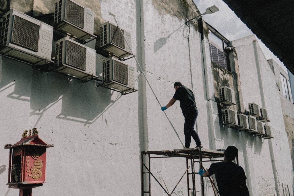 Technicien nettoyant des climatiseurs en hauteur